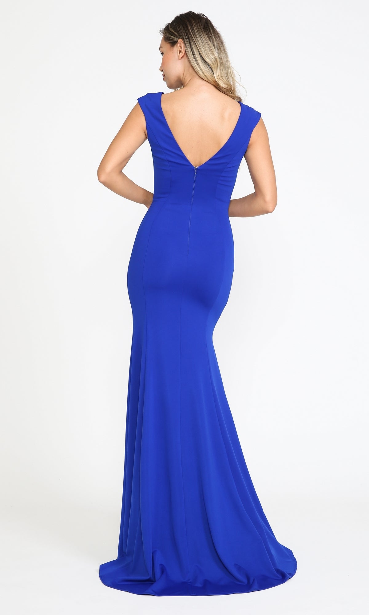 A woman wears the Cap Sleeve Long Jersey Prom Dress 8290, a floor-length fitted royal blue gown with a deep V-neck and striking V-back, standing against a plain white background.